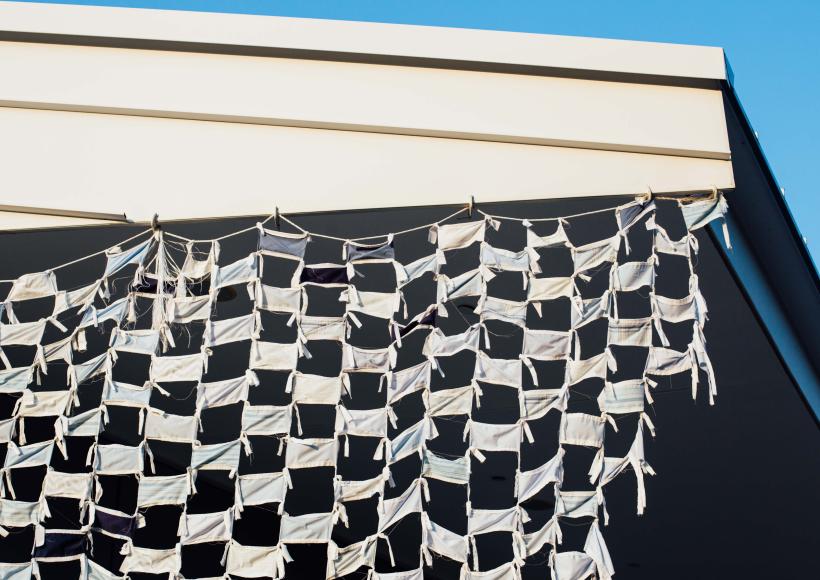 Installation view of Wave by artists Debra Everett and Ronna Nemitz. Over 2000 handmade masks blow in the wind on the exterior of MCC Art Gallery.