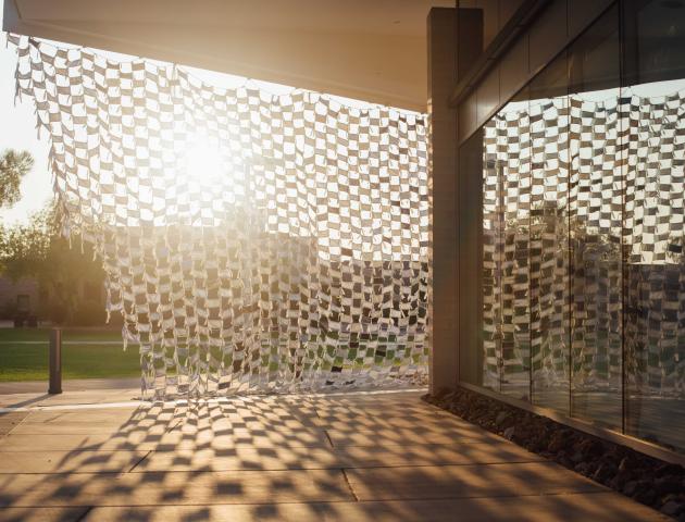 Installation view of Wave by artists Debra Everett and Ronna Nemitz. Over 2000 handmade masks blow in the wind on the exterior of MCC Art Gallery.