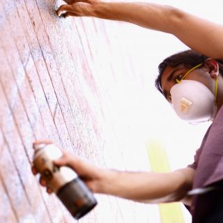 A woman spray painting a wall.