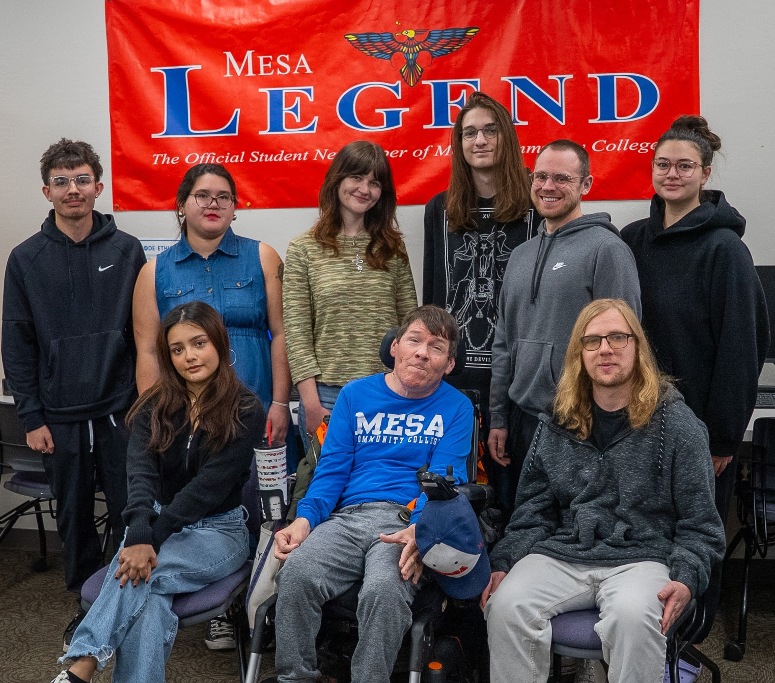 Nine journalism students in front of a Mesa Legend banner.