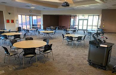 A group of round tables and chairs with a podium on the side.