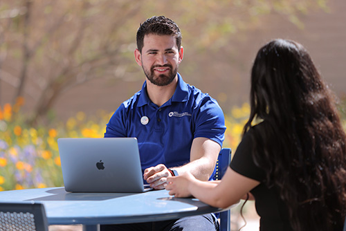 Two people sitting at an outdoor table.
