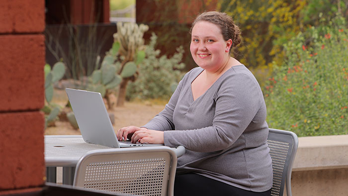 A student working on a laptop outside at the Red Mountain campus.