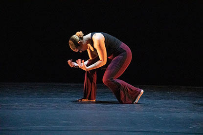 A female dancer close up on stage in a crouching position