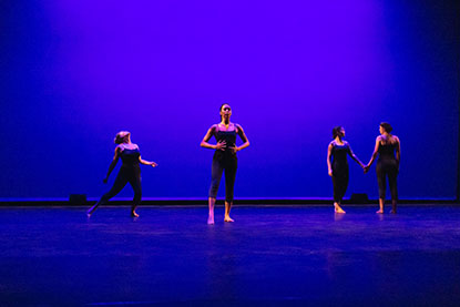 Four female dancers on stage, two holding hands