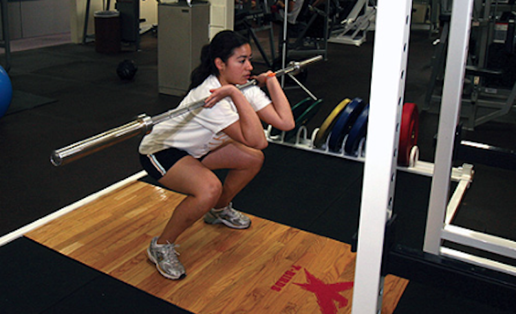 person doing exercise squats with bar