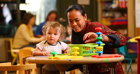 An employee and young child playing with toys at a table