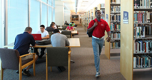 Library shelves with students sitting and walking nearby