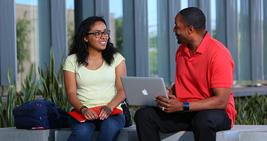 A student and employee sitting and looking at a laptop