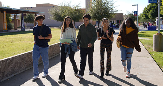A group of five students walking together on campus