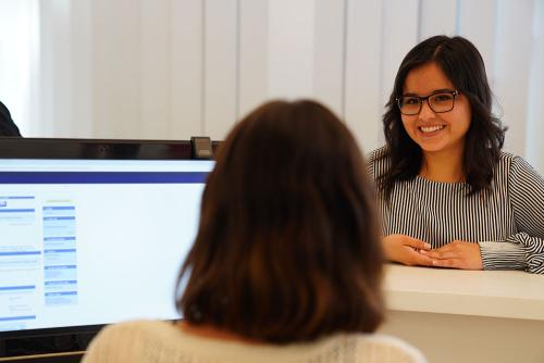 A student speaking with an employee behind a counter.