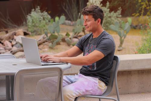 A student sitting outside on a laptop.