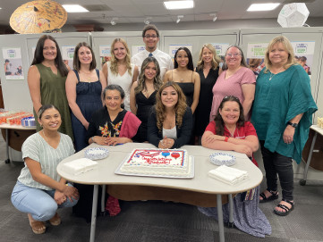 Group photo of 13 graduates, faculty and staff from EVIT and MCC Early Childhood Education smiling in front of cake.