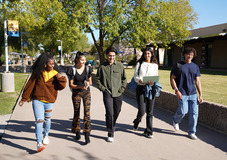 Five students walking across campus