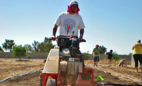 Man tilling soil with equipment.