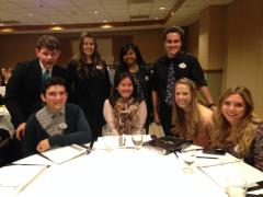 A group of students in business attire behind a round table.