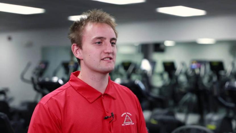 A male student facing the camera with exercise machines in the background