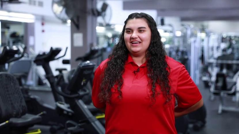 A female student facing the camera with exercise machines in the background