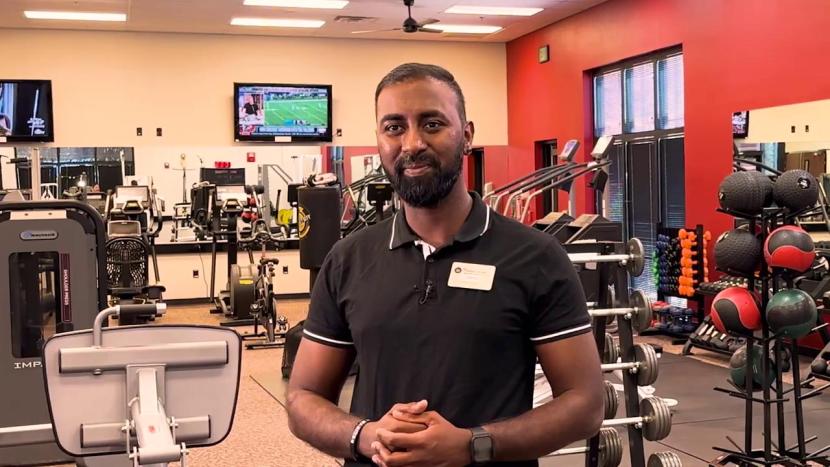 A male student facing the camera with exercise equipment in the background