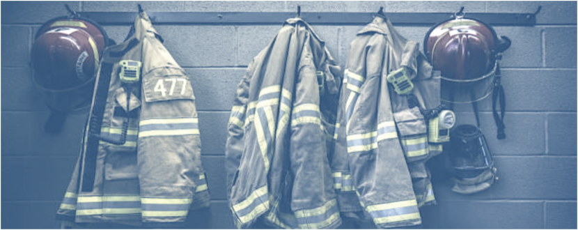 Firefighter jackets and helmets hanging on hooks on a row.