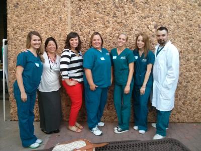 Seven people posing together, three in scrubs and one in a lab coat.