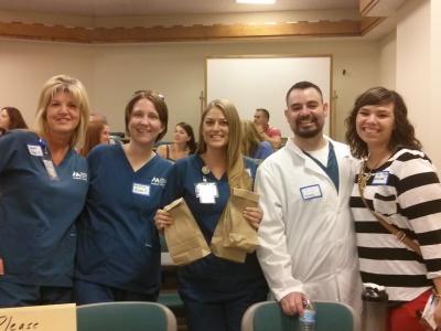 Four students posing, one holding lunch sacks.