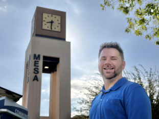 Ted Sowards in blue polo shirt standing by MCC's Clock Tower