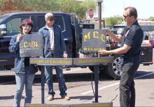 Three individuals displaying signs at groundbreaking event.