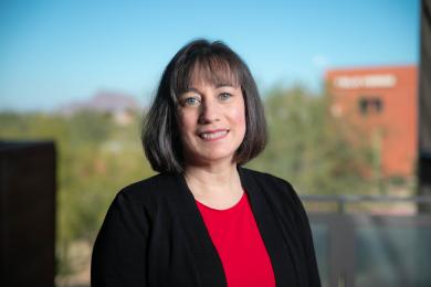 Photo of woman in black suit with red blouse smiling