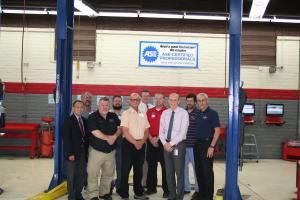 A group of faculty and administrators in an auto shop.