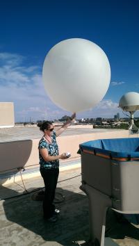 A woman holding a large inflated weather balloon.