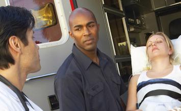 Two people doctor and EMT with patient by ambulance