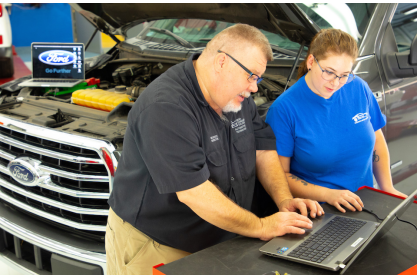 Automotive faculty and a student work on Ford compter program