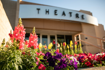 Colorful flowers with the entrance to the MCC Theatre building in the background. 