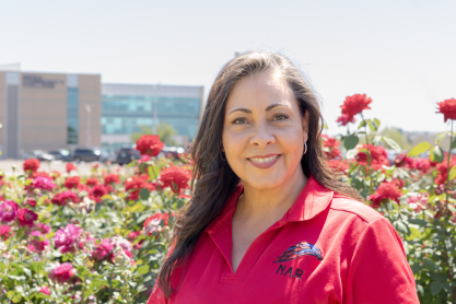 Nadine Arroyo Rodriguez in the Rose Garden at MCC with the library building in the background. 