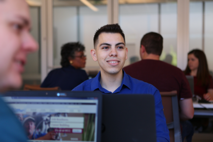 A student smiling at a computer.