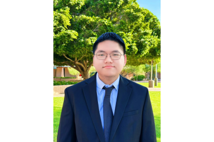 Albert Lin in a suit posing in front of mature trees.