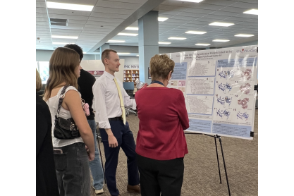 Attendees discussing a poster at the 2026 MCC Undergraduate Research Symposium.