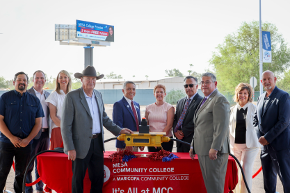 A group of elected officials, MCCCD, MCC and MCCF leadership pose by a large button to simulate the turning on of the electronic billboard promoting the Mesa College Promise program in the background. 