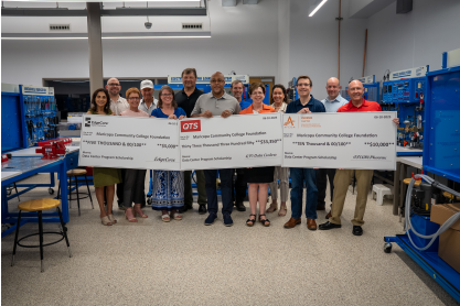 Thirteen people, representatives from MCC, Maricopa Community Colleges Foundation, EdgeCore, QTS and the Phoenix AFCOM Chapter standing behind three oversized checks representing the donations to the new Data Center Operations scholarship Fund. 