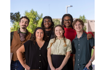 Six smiling students posing on campus.