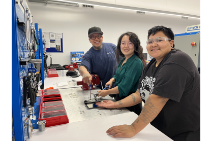 row of three students in an automated industrial technology lab
