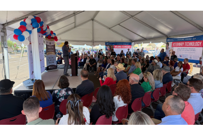 A large crowd of people seated inside a tent listening to remarks during MCC's Workforce Development Corridor Groundbreaking event. 