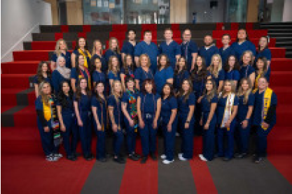 Group of nursing graduates, class of 2025, in dark blue scrubs. 