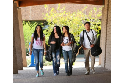 Four college students walking under an awning of a campus building. 