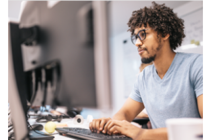 Person with a short beard and glasses working on a computer. 