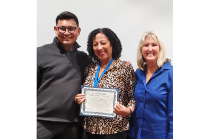 Man in grey shirt, Tawn Haupti displaying her certificate and a woman in a navy blue blouse. 