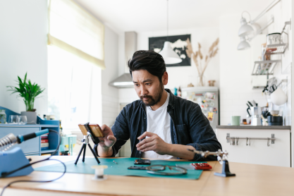 Man sitting at a desk repairing an iPhone.