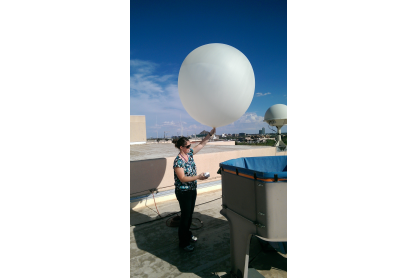 A woman holding a large inflated weather balloon.