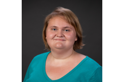 Young woman with mid-length light brown hair wearing a teal v-neck shirt.